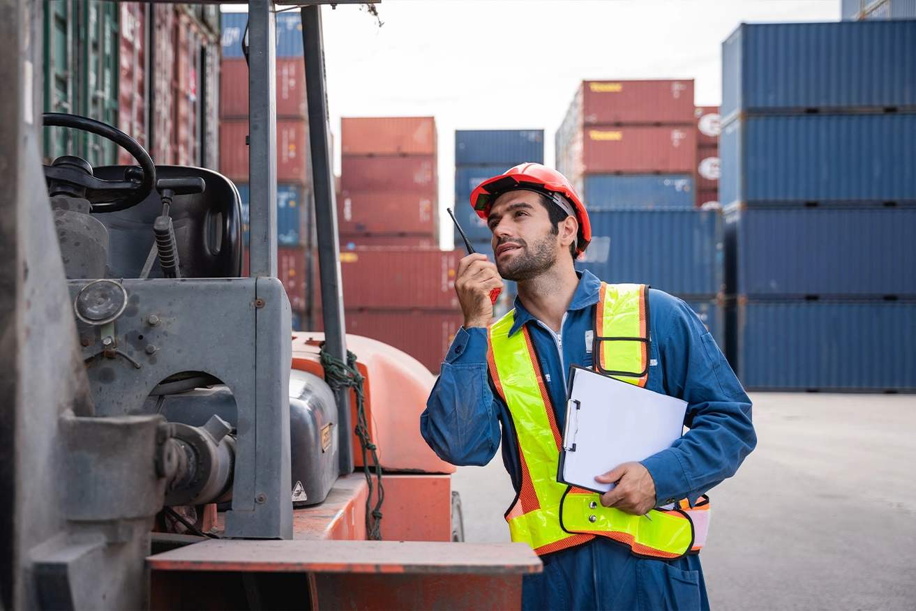 Logistiek medewerker met portofoon en klembord bij containers